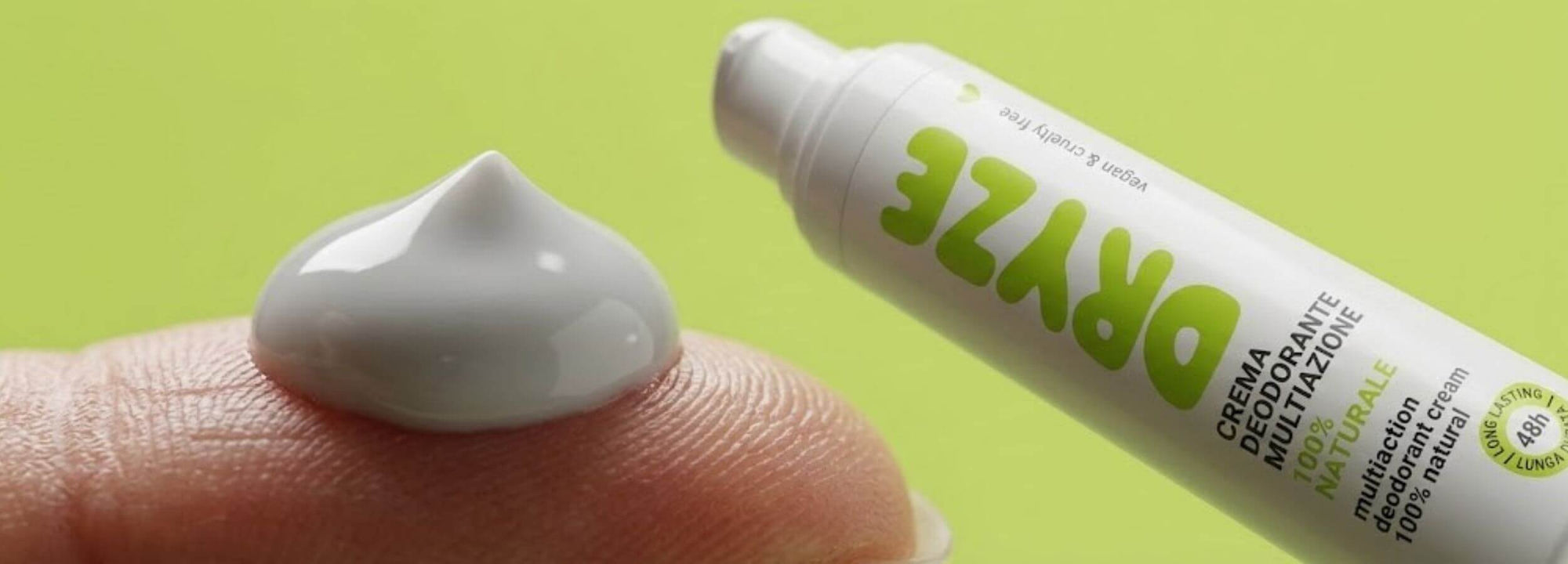 Crema Dryze applicata su un dito, flacone sullo sfondo