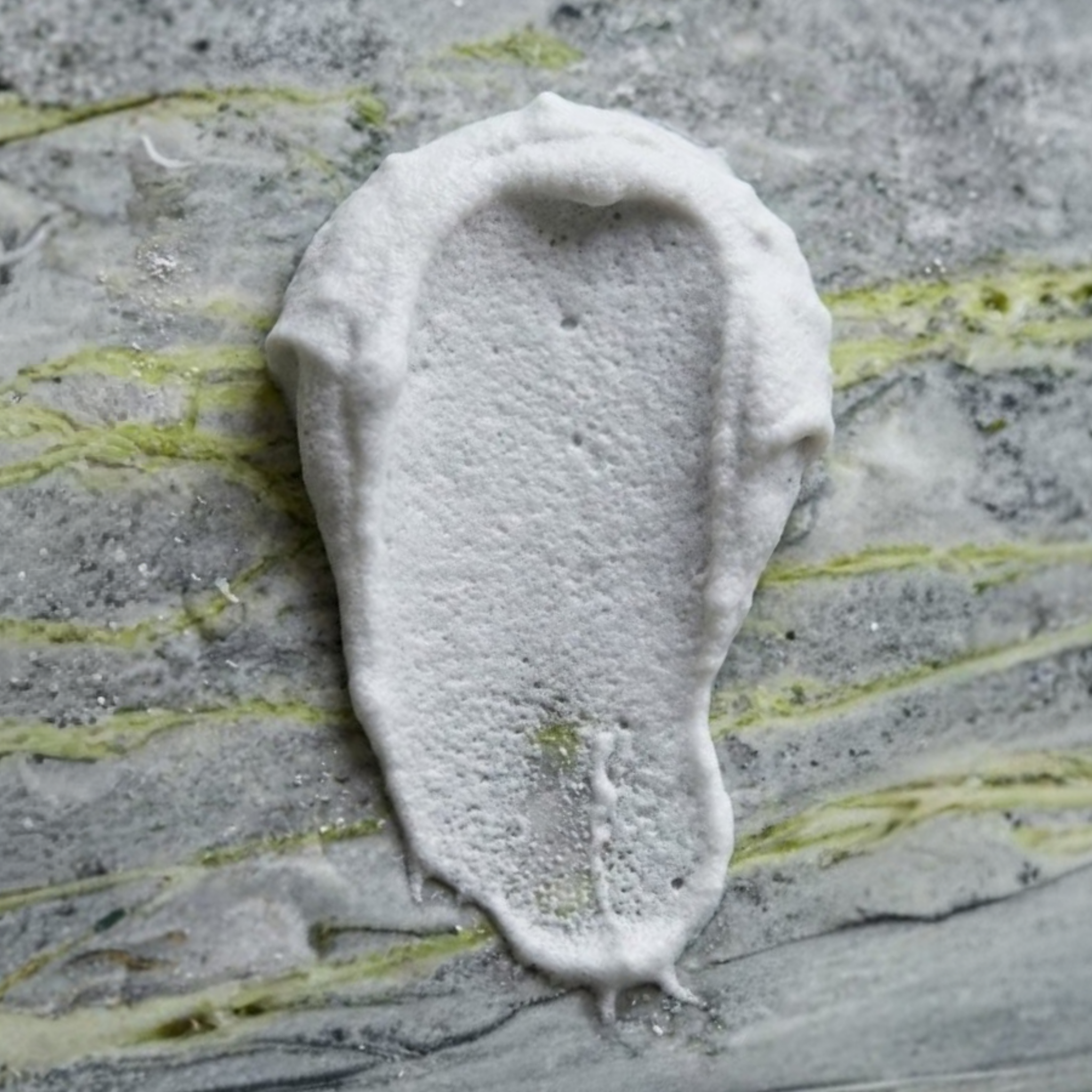 Primo piano che mostra la texture ricca e cremosa del deodorante Dryze applicato su una superficie di marmo.